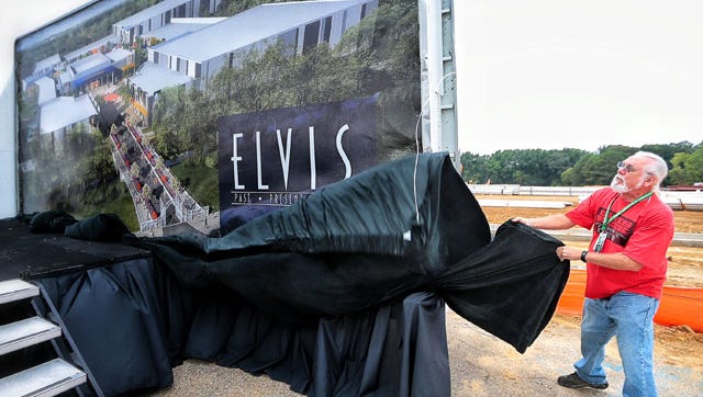 Graceland employee Bill Barmer unveils a large rendering of the new tourist facilities being built in the west side of Elvis Presley Boulevard during a press conference held by EPE officials.
