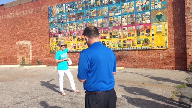 Cynthia Laney and Henry Florsheim are seen Thursday as they view a newly displayed mural downtown on the Zales building.