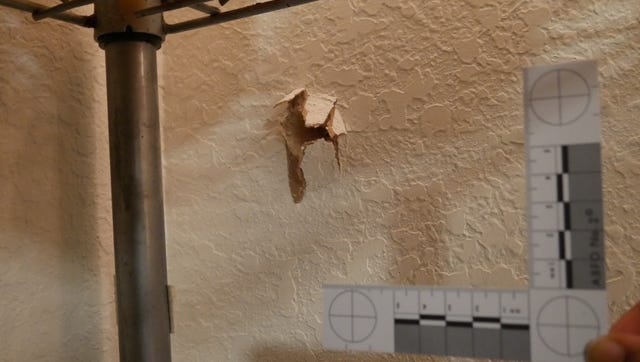 A woman's bedroom wall after  a bullet was shot through it.