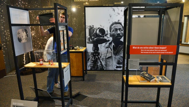 Adam Smith, curator of collections at Stearns History Museum, assembles sections of the nationally touring civil rights exhibit, “For All the World to See: Visual Culture and the Struggle for Civil Rights,” on Wednesday at the museum.