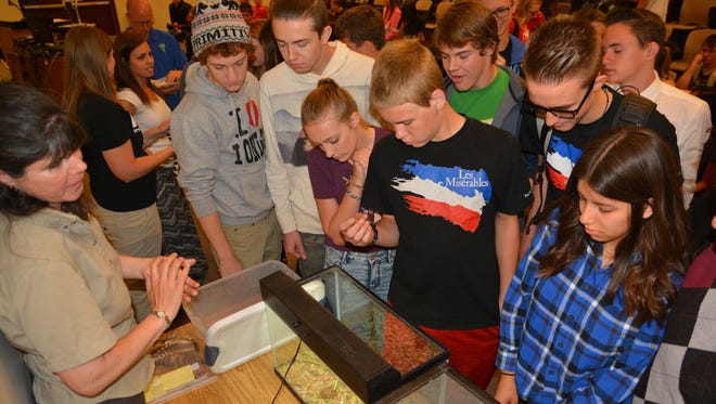 Pine View High School sophomore biology students gather around Ann McLuckie with the Utah Division of Wildlife Resources to study a juvenile desert tortoise.