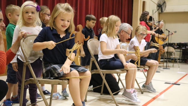 Micaela Wiechman, of Immaculate Conception School, joins other students playing a traditional wooden dancer percussion instrument during a performance by Simple Gifts on Friday.