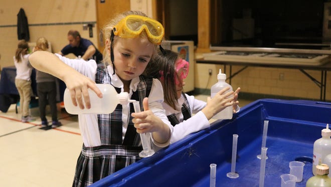Suzanna Osborne, first grade student at Immaculate Conception School, tries an experiment to test the pH level of various liquids.