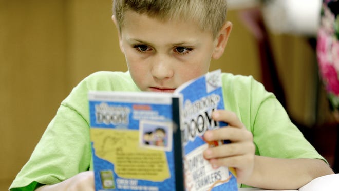 Second-grader Owen Tompkins is absorbed in a book he is reading in Tammy Charlier's classroom at Red Smith School.