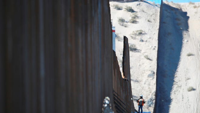 A worker is dwarfed by the border fence which is under construction Jan. 25, 2017, in Sunland Park, N.M. across from Anapra in Ciudad Juarez, Mexico.