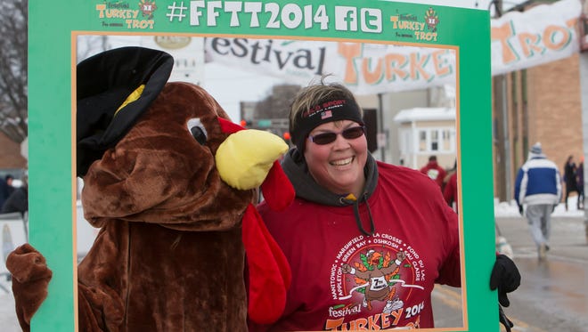 People begin their Thanksgiving Day with a walk or run through the streets in Oshkosh for the 7th annual Festival Foods Turkey Trot. Nancy Folk poses with the turkey mascot.