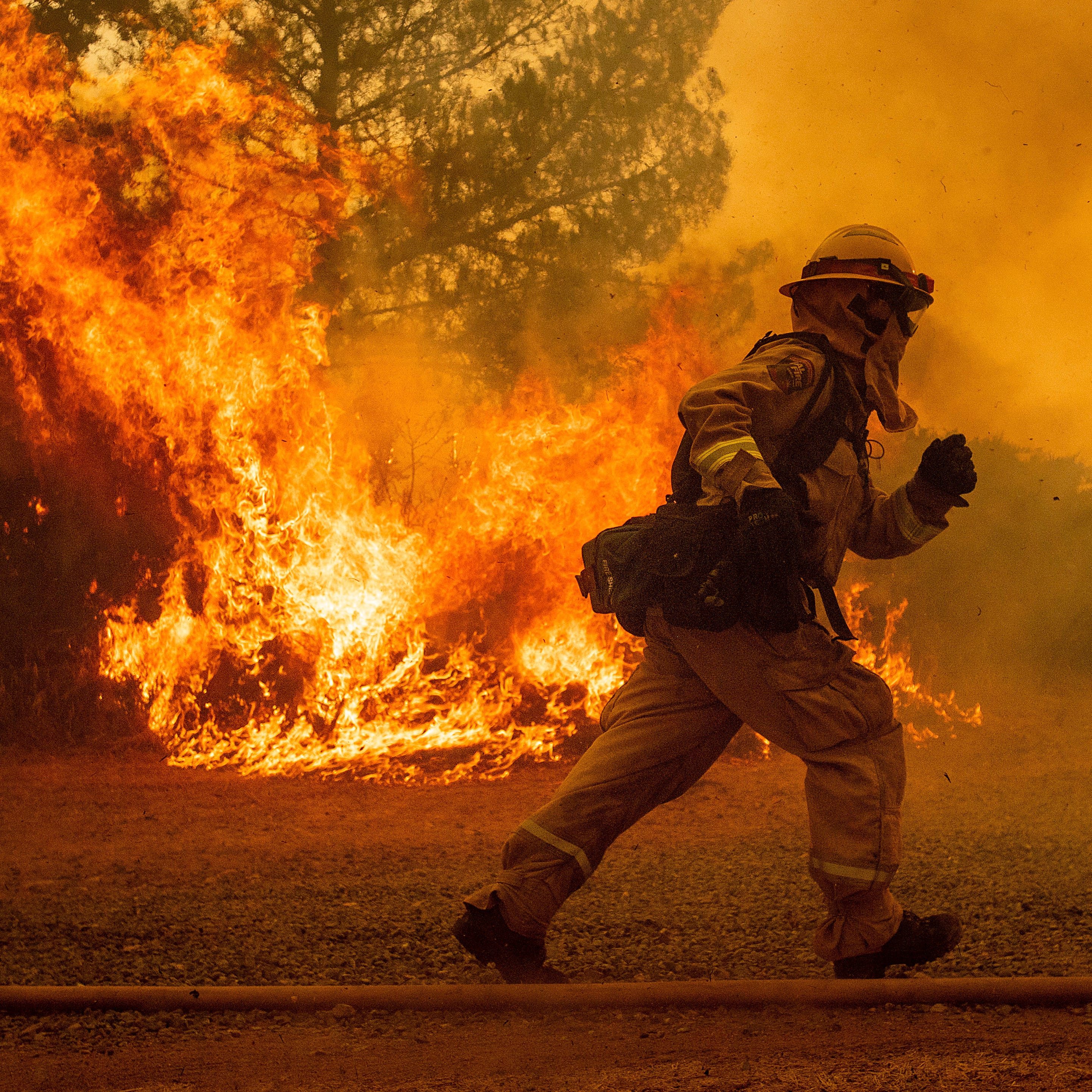 A firefighter runs while trying to save a home as a wildfire tears through Lakeport, Calif. The residence eventually burned.