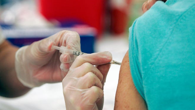 A Walgreen’s pharmacy manager injects a costumer with the seasonal flu vaccine in Columbia, South Carolina.