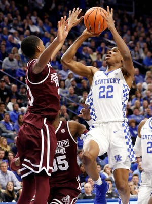 Kentucky's Shai Gilgeous-Alexander (22) shoots while defended by Mississippi State's Tyson Carter, left, and Aric Holman (35) during the first half of an NCAA college basketball game, Tuesday, Jan. 23, 2018, in Lexington, Ky.