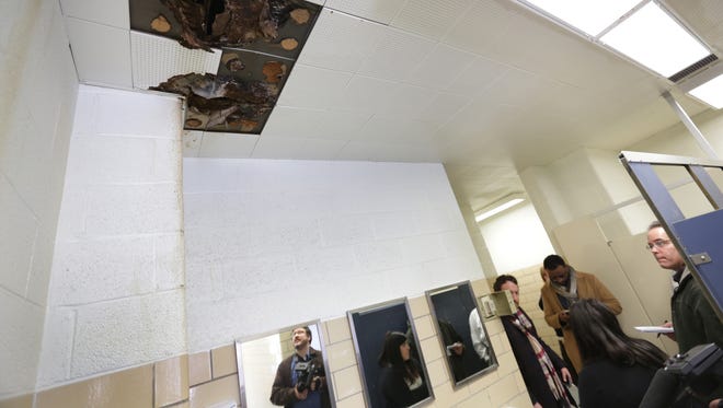 Members of the American Federation of Teachers look at some missing ceiling tiles and mold in a faculty restroom at Osborn Collegiate Academy of Mathematics Science and Technology in Detroit on Thursday, Jan. 14, 2016.