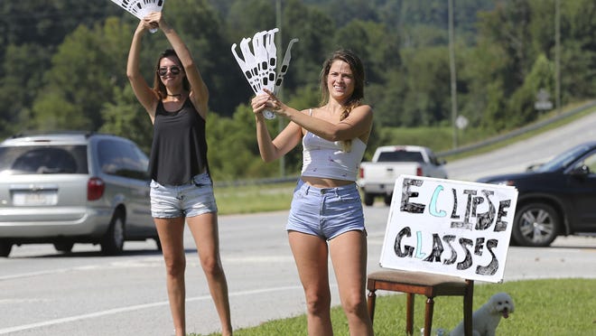 Ashley Ann Sander, left, and Alexandra Dowling hawk solar eclipse glasses for $10 a pair on the side of the road to tourists approaching Clayton, Ga., Sunday, Aug. 20, 2017. Clayton is in the path of totality in North Georgia. (Curtis Compton/Atlanta Journal-Constitution via AP)