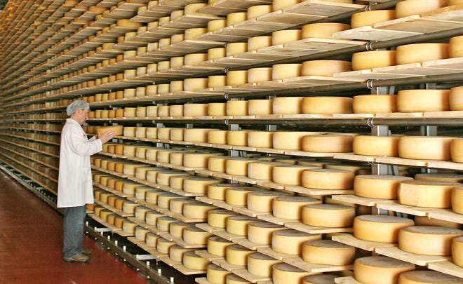 A worker inspects wheels of Gruyere at Roth Kase USA. A judicial ruling has determined that “gruyere” is a generic style of cheese that can come from anywhere. The decision reaffirms that all cheesemakers, not just those in France or Switzerland, can continue to create and market cheese under this common name.