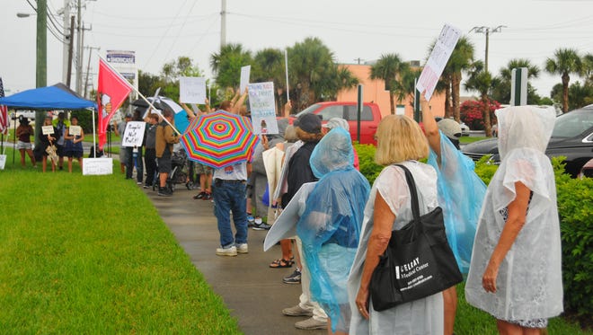 A group of protesters stands in the rain outside of Comprehensive Health Services global headquarters in Cape Canaveral in early July, decrying the Trump administration's  zero-tolerance crackdown allowing separating immigrant children from their parents.
