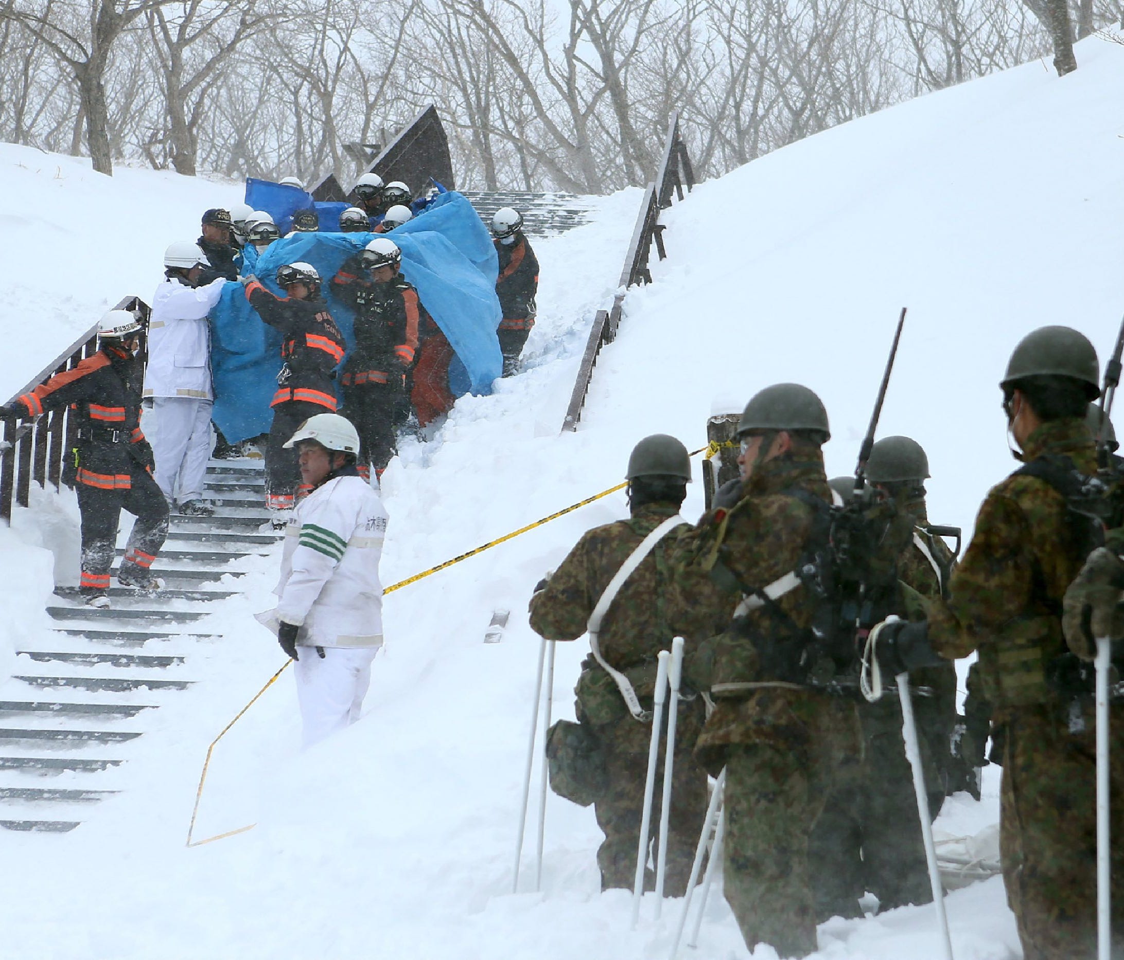 Firefighters carry a survivor they rescued from the site of an avalanche in Nasu town, Tochigi prefecture on March 27, 2017.