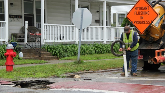 Anson Gordon of the Burlington Department of Public Works drains water around a sinkhole at the intersection of Central Avenue and Wright Avenue on Sunday.