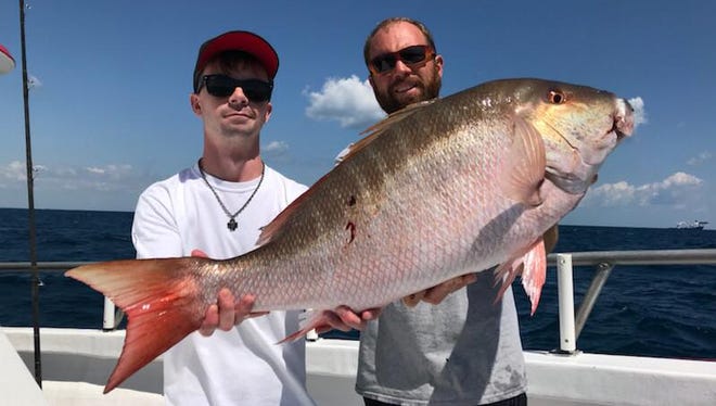 Angler Mike Britain (left) and Capt. Brian Godwin (right) hoist the 22-pound mutton snapper Britain caught Monday aboard Lady Stuart partyboat out of Hutchinson Island Marriott Marina in Stuart.