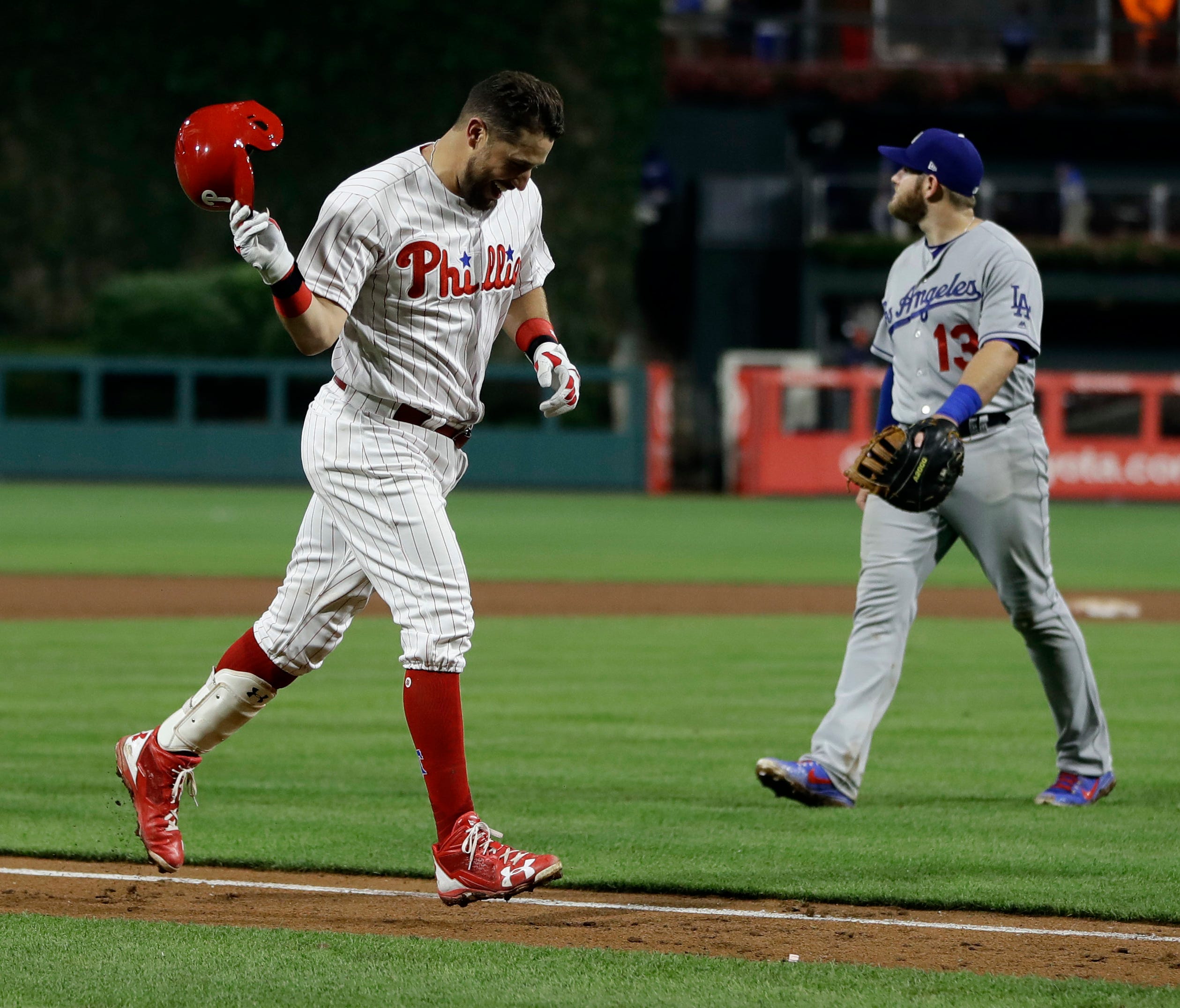 Philadelphia Phillies' Trevor Plouffe, left, celebrates past Los Angeles Dodgers first baseman Max Muncy after hitting the game-winning, three-run home run off relief pitcher Kike Hernandez during the 16th inning.