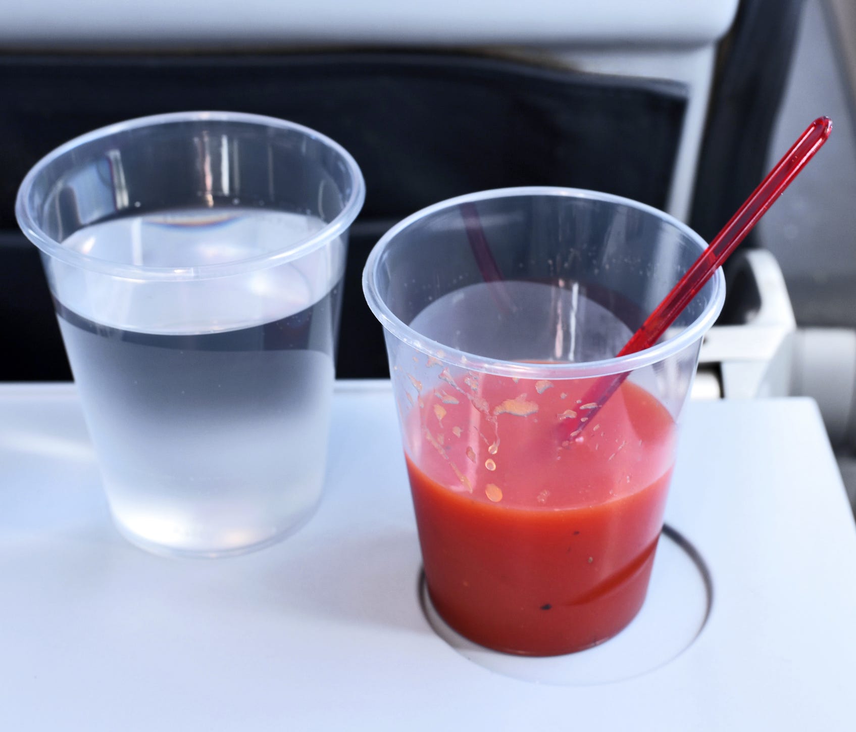 Drinks on a flight. Tomato juice and water glass on a table in an airplane.