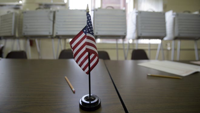 In this 2005 file photo, an American flag sits on the table top in front of the voting booths at the polling station for the 11th precinct at St. Johns Presbyterian Church in Detroit.