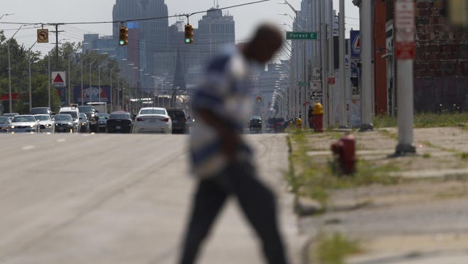 A pedestrian crosses Gratiot Avenue in Rep. Rashida Tlaib's, D-Mich., 13th district in Detroit, Monday, July 15, 2019. Injecting race into his criticism of liberal Democrats, President Donald Trump said four congresswomen of color, including Tlaib, should go back to the "broken and crime infested" countries they came from, ignoring the fact that all of the women are American citizens and three were born in the U.S. (AP Photo/Paul Sancya)