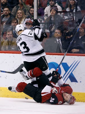 Arizona Coyotes' Klas Dahlbeck (34), of Sweden, falls to the ice as he collides with Los Angeles Kings' Dustin Brown during the second period of an NHL hockey game, Saturday, Dec. 26, 2015, in Glendale, Ariz.