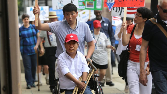 Oidov Vaanchig of Ulan Bator, Mongolia, center, participates in the disability pride walk Monday. There's nothing like the Americans with Disbaility Act in his country, he said. "It's easier to count the places where you can go than to count the places where you cannot go."