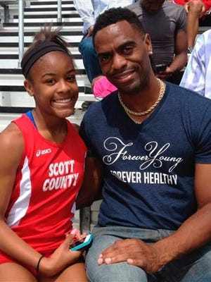In this May 3, 2014, photo, Trinity Gay, a seventh-grader racing for her Scott County High School team, poses for a photo with her father Tyson Gay, after she won the 100 meters and was part of the winning 4-by-100 and 4-by-200 relays at the meet in Georgetown, Ky. The 15-year-old daughter of Olympic sprinter Tyson Gay was fatally shot in the neck, authorities and the athlete's agent said Sunday, Oct. 16, 2016, and police have arrested a man in connection with the shooting. (Mark Maloney/Lexington Herald-Leader via AP)