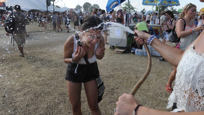 Cata Valencia gets cooled off by Christina Parsons who was hosing people down from the heat at the  Bonnaroo Music and Arts Festival on Saturday June 13, 2015, in Manchester.