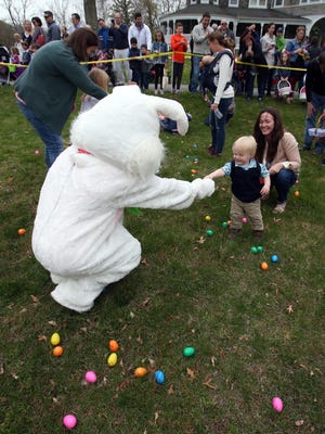 Calvin Gallagher, 20 months, of Wilmington, accepts an egg from the Easter Bunny during the Easter egg hunt for the smallest hunters at Auburn Heights Preserve Saturday.