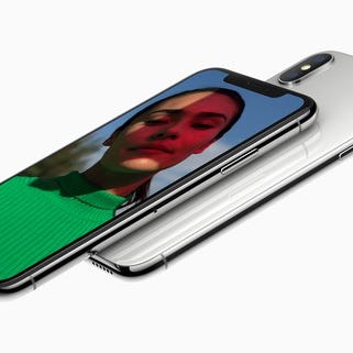 One Apple iPhone X faceup and pointing to the left with another iPhone X, this time face down, underneath it.