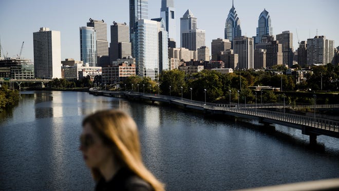 A woman crosses the South Street Bridge spanning the Schuylkill River and view of the Philadelphia skyline, Wednesday, Oct. 18, 2017. The cities of Philadelphia and Pittsburgh are both attempting to draw Amazon to build its second headquarters in Pennsylvania. (AP Photo/Matt Rourke)