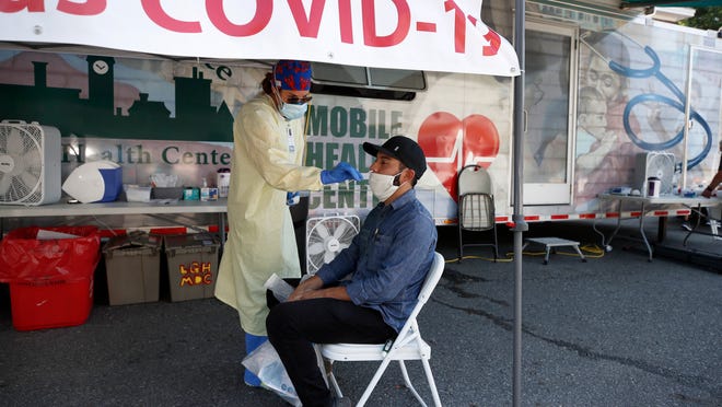 Nurse Tanya Markos administers a coronavirus test on patient Ricardo Sojuel at a mobile COVID-19 testing unit, Thursday, July 2, 2020.