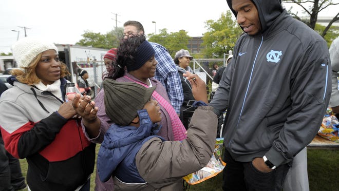 Eric Ebron, right, says, "I'll give you my autograph after you take this bag of food," to Jaylen Nevitt, foreground, 9, as his mother, Jasmin Bennett, background-right, 36, and Burnetta Taylor, left, 45, all of Detroit, wait to take a picture with the Lions’ player.