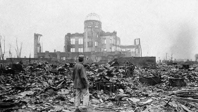In this Sept. 8, 1945 file photo, an allied correspondent stands in the rubble in front of the shell of a building that once was a movie theater in Hiroshima, Japan, a month after the first atomic bomb ever used in warfare was dropped by the U.S. on Monday, Aug. 6, 1945. In a moment seven decades in the making, President Barack Obama this month will become the first sitting American president to visit Hiroshima, where the U.S. dropped an atomic bomb during World War II, decimating a city and exploding the world into the Atomic Age.