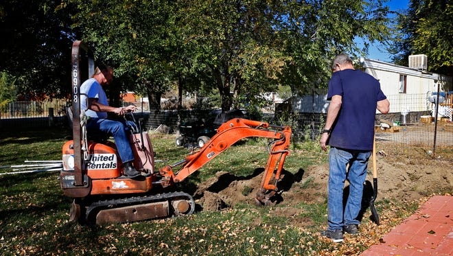 Jerry Foxwell, left, and Mike McCoy work to extend an irrigation line Tuesday at McCoy's home in the Harvest Gold subdivision in Bloomfield.