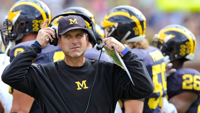 Michigan coach Jim Harbaugh walks back to the sidelines after talking to his players during a timeout in the fourth quarter.