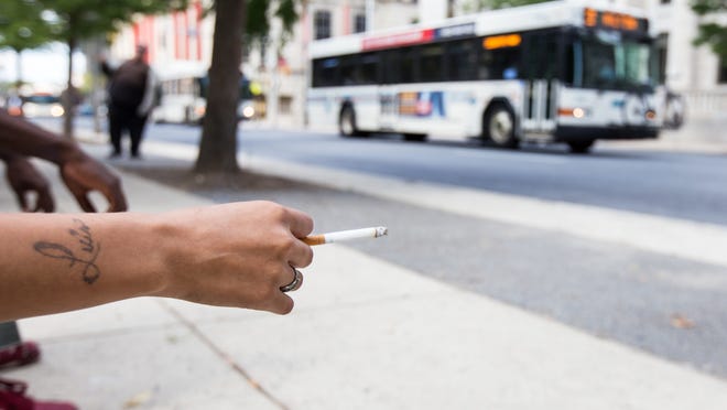 
A woman holds a cigarette as she waits near a bus stop at Rodney Square on June 26. Mayor Dennis P. Williams signed an executive order that bans smoking in outdoor public places in Wilmington.
