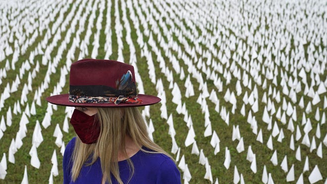 Artist Suzanne Brennan Firstenberg stands among thousands of white flags planted in remembrance of those who have died of COVID-19 in the U.S. The art installation, 2 miles from the U.S. Capitol, was inspired by Lt. Gov. Dan Patrick's comments suggesting that older people should be willing to sacrifice their lives so that the economy could reopen amid the coronavirus pandemic.