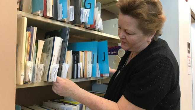 Redding Library employee Laurie Figuero checks for a book that had been put on hold by a patron. The Redding Library is proposing to raise some fees and start a new fine for people who don't pick up their held items in time.