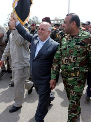 Prime Minister Haider al-Abadi, center, walks with a member of Iraqi Shiite volunteers in the city of Tikrit after its recapture from Islamic State militants on April 1, 2015.