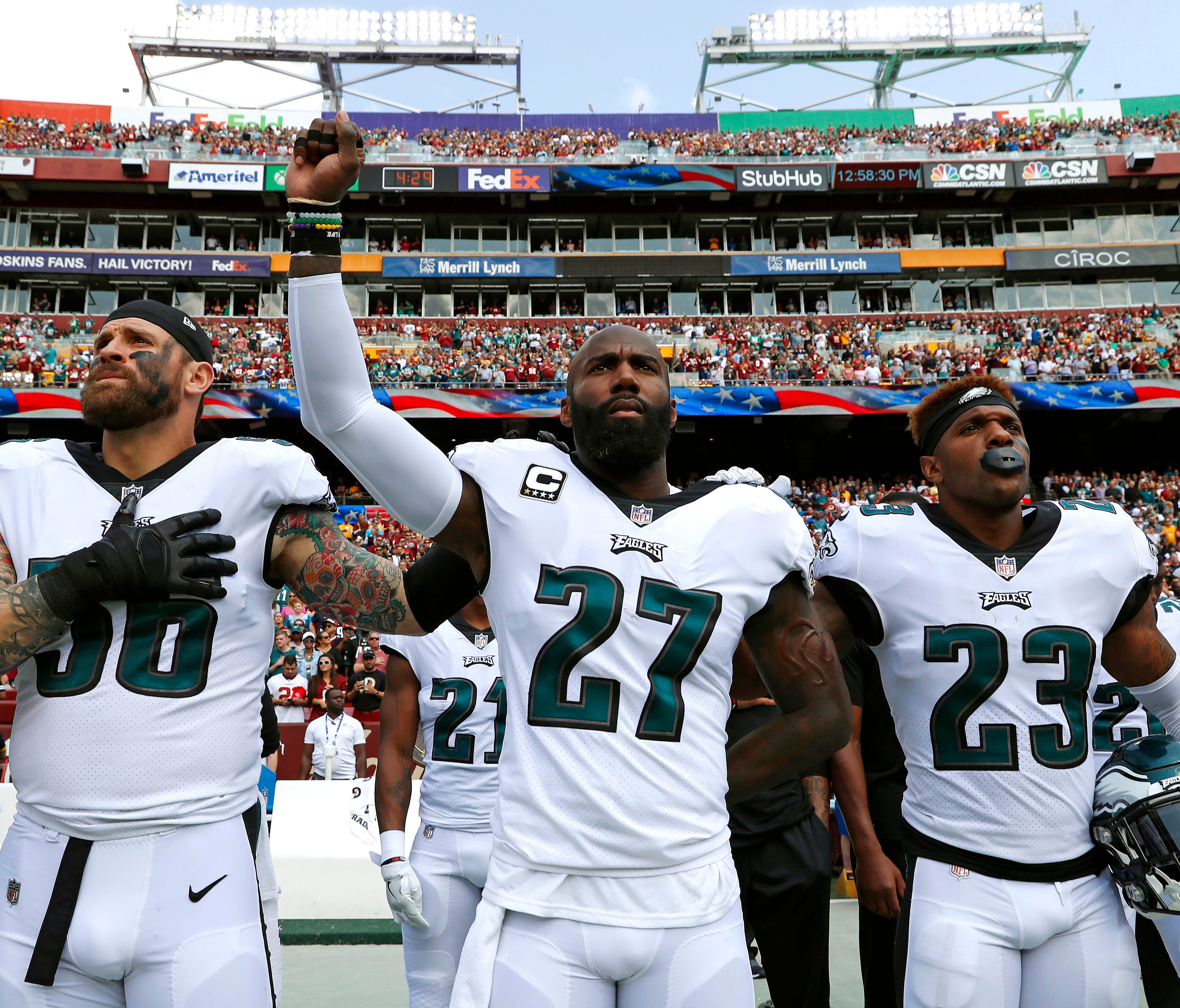 Philadelphia Eagles strong safety Malcolm Jenkins (center) raises his fist as he stands between teammates Chris Long (left) and Rodney McLeod (right) during the national anthem before an NFL game against the Washington Redskins.