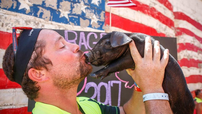 Zach Wigle din Solon sărută un pui de porc Ouă la standul Swine Cuddles din West Bend în timpul RAGBRAI pe 24 iulie 2017.