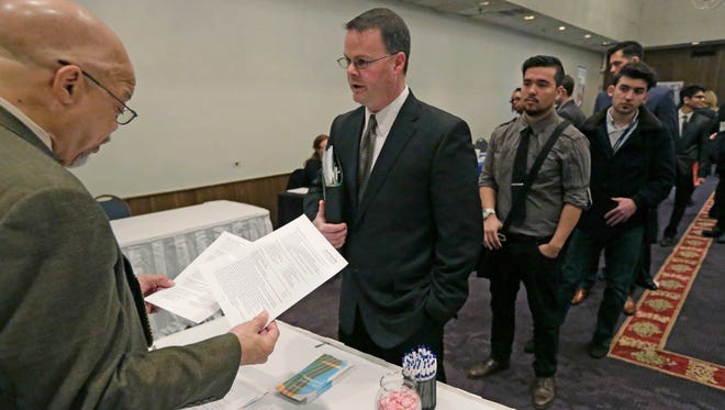 In this April 22, 2015 photo, Ralph Logan, general manager of Microtrain, left, speaks with job seekers.