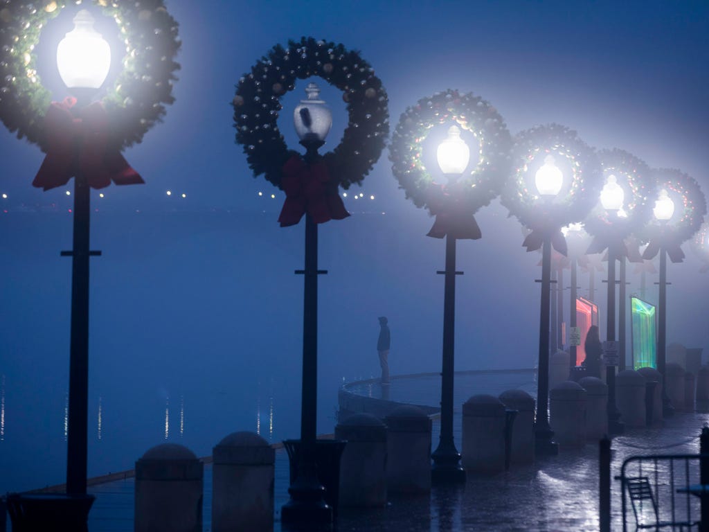 A man watches as the dense fog comes off the Potomac River at dusk at the Georgetown waterfront in Washington, D.C.