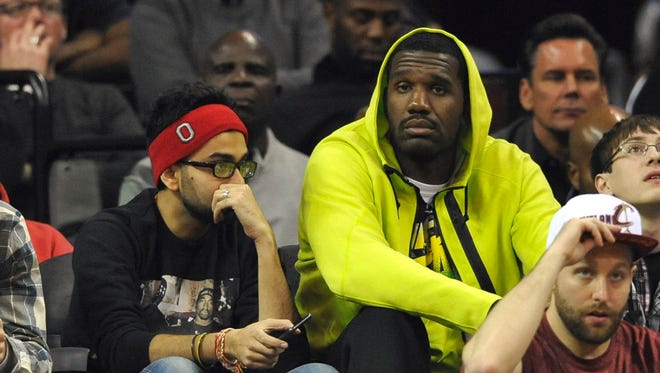 Nov 22, 2014; Cleveland, OH, USA; Former player Greg Oden (R) sits near the Cleveland Cavaliers bench in the second quarter at Quicken Loans Arena.