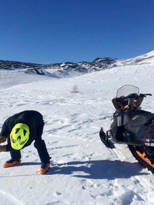 A snow-machine rider takes a snowpack reading as part of Community Snow Observations, a NASA-sponsored citizen science project.