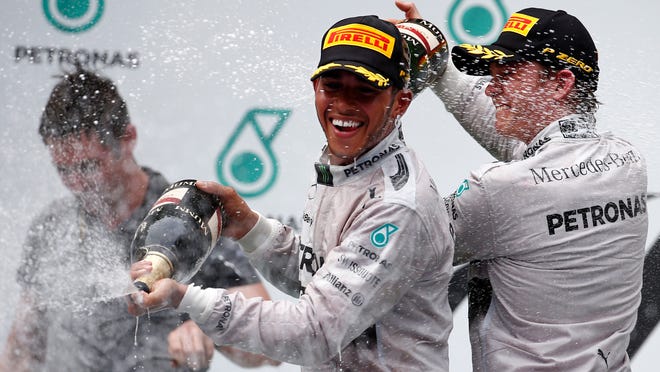 Mercedes driver Lewis Hamilton of Britain sprays champagne on the podium with teammate Nico Rosberg, right, after winning the the Malaysian Formula One Grand Prix at Sepang International Circuit in Sepang, Malaysia, Sunday, March 30, 2014. Rosberg finished in second place. (AP Photo/Vincent Thian)