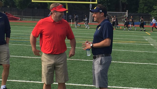 Michigan passing game coordinator Jedd Fisch, right, and Georgia football coach Kirby Smart talk during a satellite camp Thursday, June 2, 2016, in Atlanta.