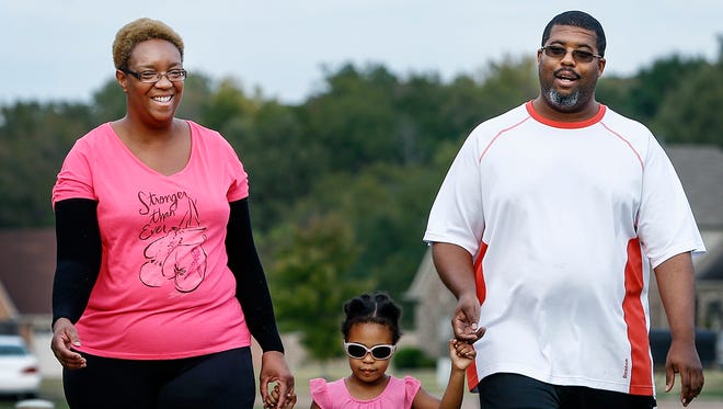 Breast cancer survivor Kari Daniel takes a walk with husband Corey and their 3-year-old daughter Amira outside their South Memphis home while preparing for this weekend's Susan G. Komen Race for the Cure.