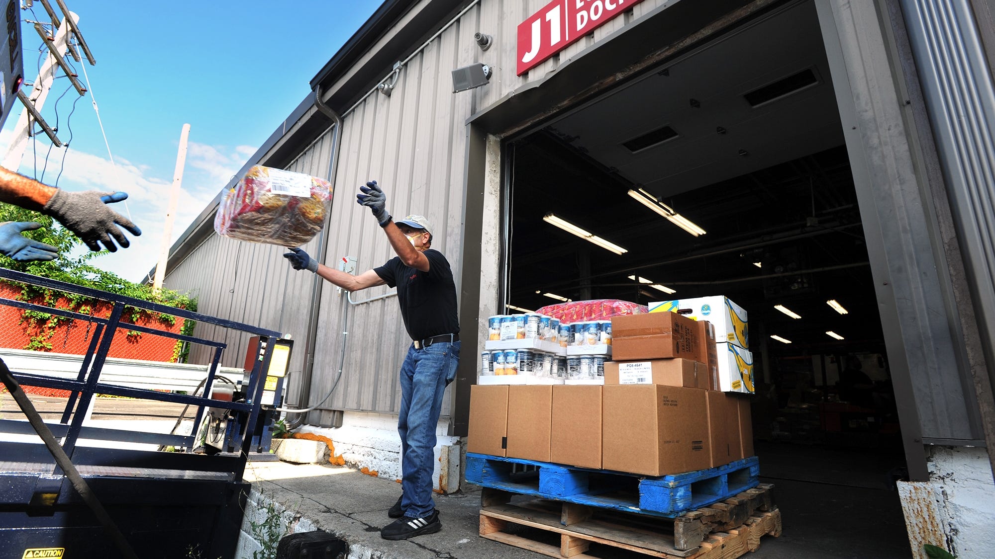 Guillermo Viscarra, a volunteer from the Franklin Food Pantry, throws boxes of food to Andy Keesan, not pictured, at the United Way of Tri Country food warehouse in Framingham, Massachusetts, last year.